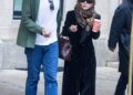 two individuals walking together on a city street one holding a beverage