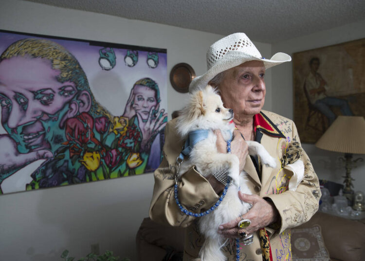Monti Rock III with his dog Zozo, in a home decorated with paintings and memorabilia devoted to ...