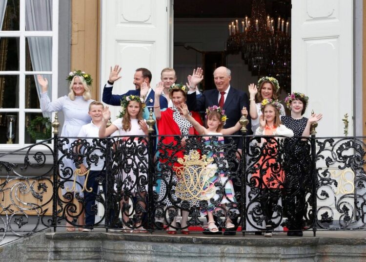 A group of people in formal attire standing on a balcony and waving