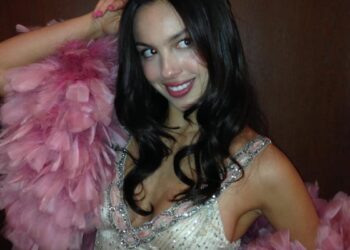 A person dressed in a glamorous outfit with a tiara and feather boa.