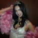 A person dressed in a glamorous outfit with a tiara and feather boa.