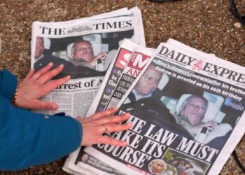 A journalist looks at newspaper front pages on Feb. 20, 2026.