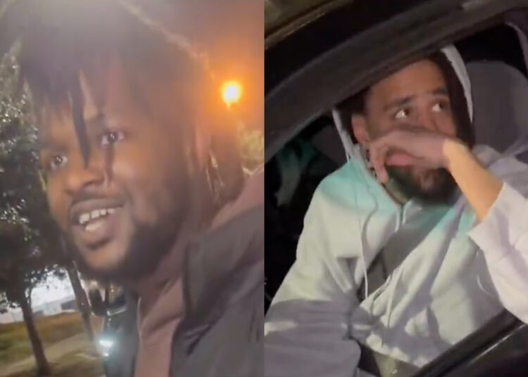 A man leans into a car window, talking to two men inside at night, one of whom is J. Cole. Trees and streetlights are visible in the background.