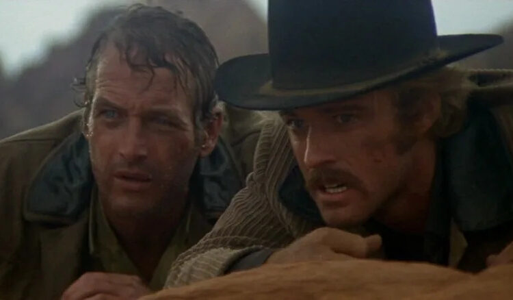 Paul Newman as Butch Cassidy and Robert Redford as the Sundance Kid crouching behind a rock in Butch Cassidy and the Sundance Kid