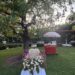 A decorated outdoor space with floral arrangements and a hot dog cart.