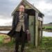 Timothy Spall standing outside a run-down bus shelter in The Last Bus