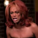 Tyra Banks on a reality show set, appearing intense and expressive, with voluminous styled hair and a strapless dress