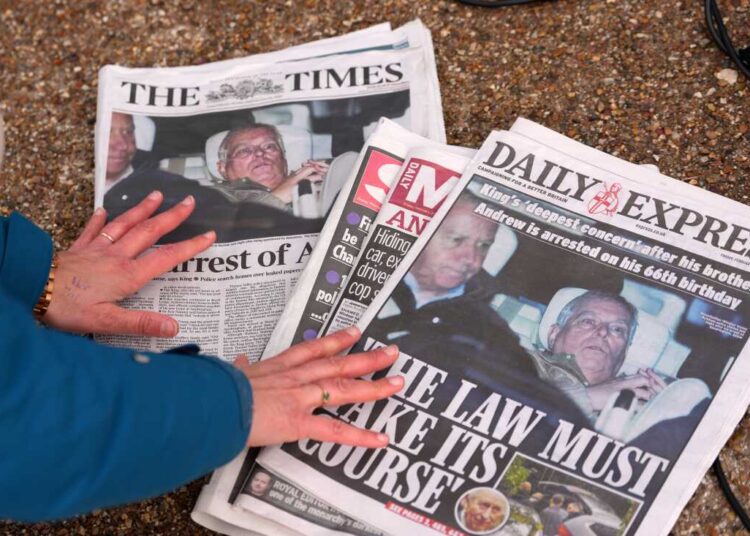 A journalist looks at Friday's newspaper front pages in London after Andrew Mountbatten-Windsor was arrested and held for hours by British police on suspicion of misconduct in public office related to his links to Jeffrey Epstein.