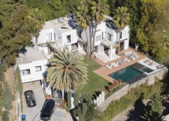 Modern two-story house with a pool and palm trees.