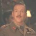 A man in a military uniform smirks