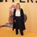 Amanda Holden smiles while wearing a Holland Cooper white shirt, black trousers and a long black coat