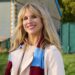 Amanda smiles, wearing a trench coat and football scarf, in Amandaland