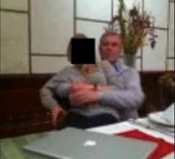 A blurry photo of a woman sat on a man's lap