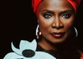 Angélique Kidjo - Photo by Brantley Gutiérrez. Angélique wearing a turban and a dress with a large flower on the shoulder.