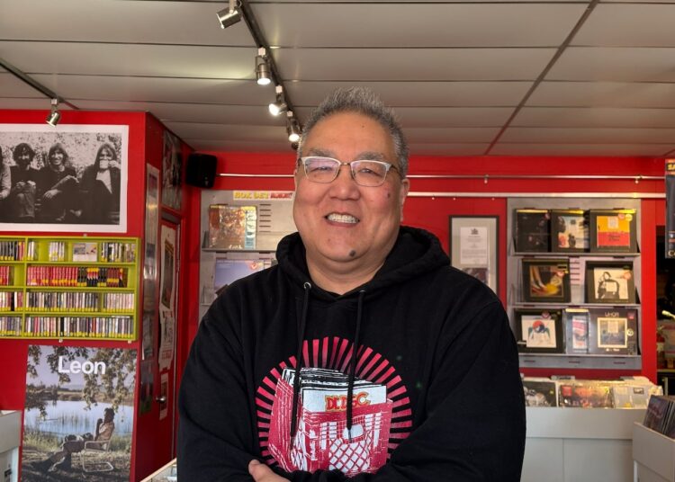 A man in a record store smiles at the camera