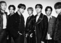 Black and white image of BTS members posing together in stylish outfits.