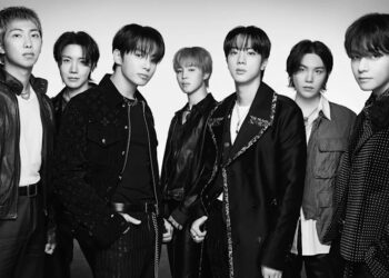 Black and white image of BTS members posing together in stylish outfits.