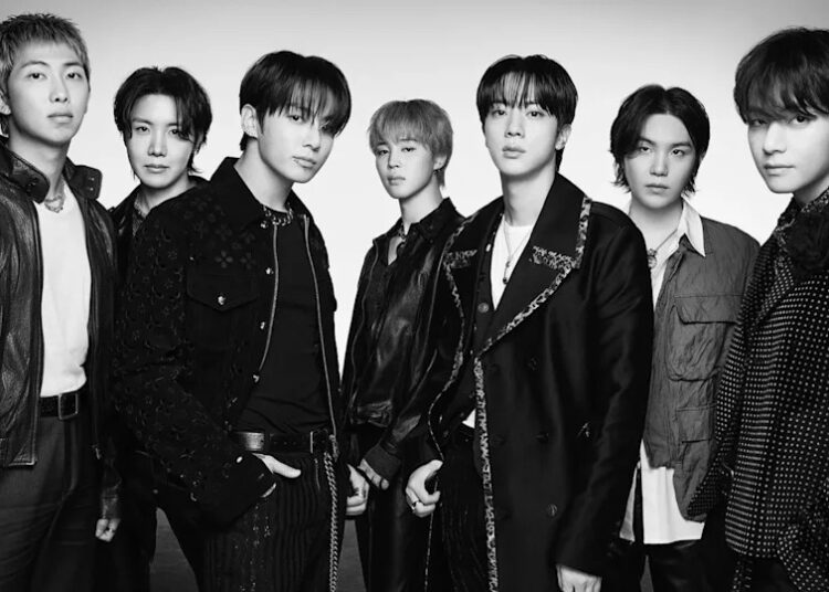 Black and white image of BTS members posing together in stylish outfits.
