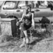 beau garrett sitting on a chair in front of an old vehicle, surrounded by grass