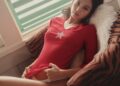A person lounging on a couch by a window.