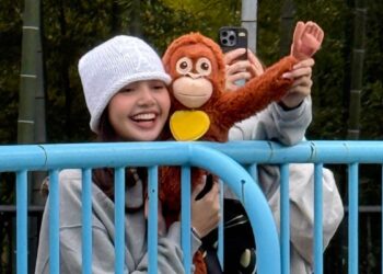 Individuals holding a stuffed toy at a park