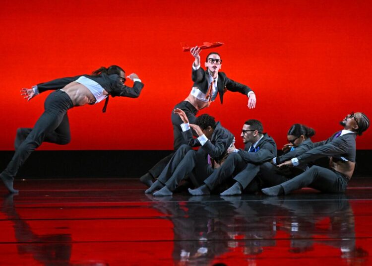 Dancers in suits on a red stage.