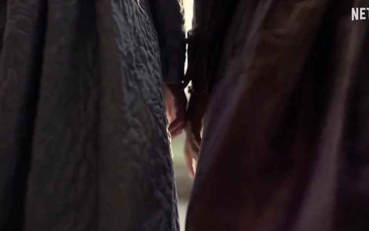 Francesca Bridgerton and Michaela Stirling's hands touch.