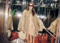 person in a stylish outfit holding a decorative bag in a reflective environment