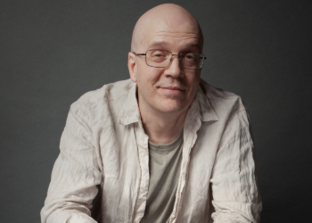 Devin Townsend sitting in a professional studio, looking thoughtful and surrounded by music equipment.