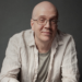 Devin Townsend sitting in a professional studio, looking thoughtful and surrounded by music equipment.
