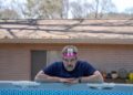 a person resting on the edge of a swimming pool with a card on their forehead