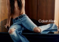 Dakota Johnson sits on a piano in jeans.