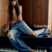 Dakota Johnson sits on a piano in jeans.