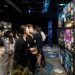 two college-aged adults smile up at backlit art displays down a long dark corridor lit by commercial art