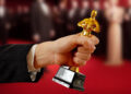 a hand holding an Oscar statue