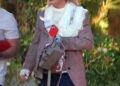 Britney Spears wearing sunglasses, a brown blazer, a white lace top, and blue jeans, walking outdoors.