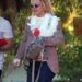 Britney Spears wearing sunglasses, a brown blazer, a white lace top, and blue jeans, walking outdoors.