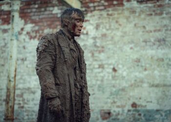 person covered in mud standing against a brick wall