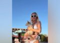 Brittany Snow posing in a white ribbed bikini and mod sunglasses while holding a small dog and a disco ball cup.