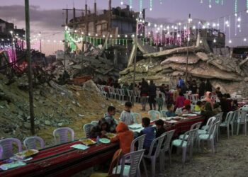 Palestinians sit at a long table amid the rubble of destroyed buildings as they gather for iftar, the fast-breaking meal, during the Muslim holy month of Ramadan in Khan Younis, Gaza Strip, Thursday, Feb. 19, 2026. (AP Photo/Abdel Kareem Hana)