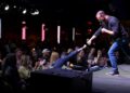 A man on stage fist bumps an audience member