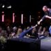 A man on stage fist bumps an audience member