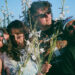 Members of Mild Universe band posing with flowers outdoors