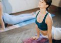 Two women practicing yoga on mats in a bright room.