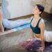 Two women practicing yoga on mats in a bright room.