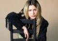 Slayyyter sits backward in a chair.