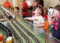 a child looking at a model train set.