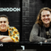Hannah Bruce and James Taylor are leaning on a black metal bar. She is on the left wearing a flowery short and has short hair. He is on the right, has long hair and is wearing a grey jumper. Behind them is a black wall with 'The Bullingdon' in white writing.