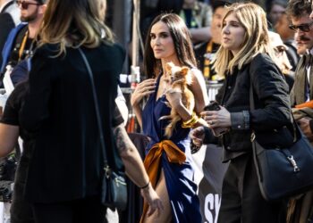 Demi Moore walks in a crowd of people while carrying her dog.