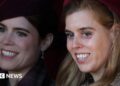 Princesses Eugenie and Beatrice, seen in close-up, smiling and looking off camera - they are both wearing coats and hats